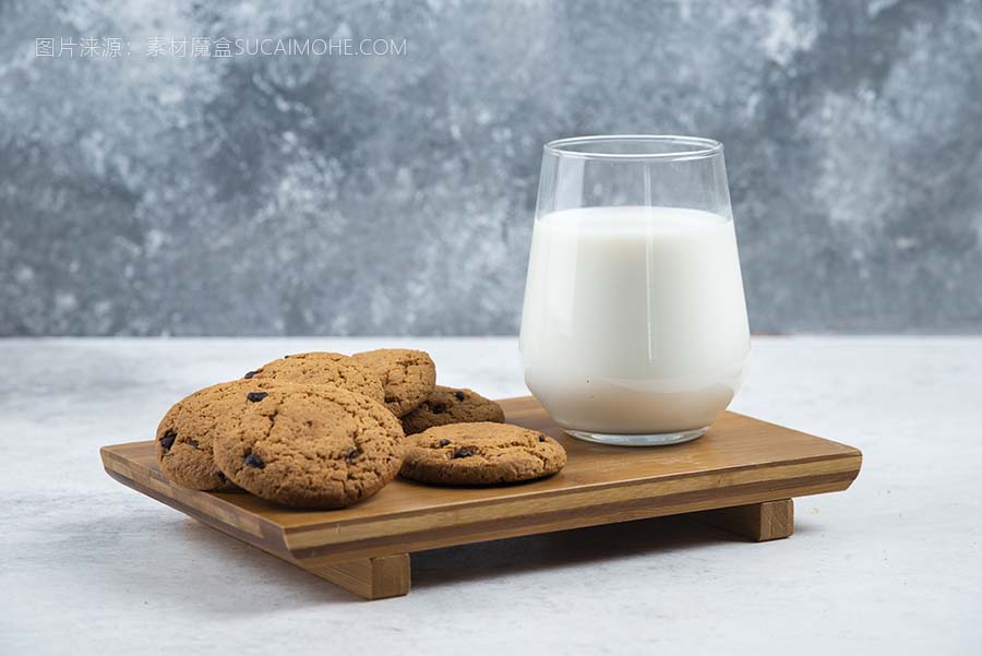 一个玻璃杯，在木桌上放着巧克力饼干