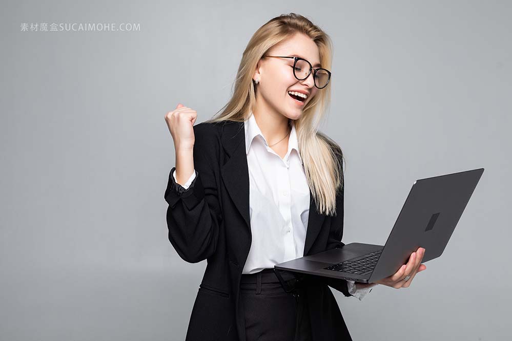 一个年轻的快乐商业女人肖像与一台笔记本电脑，用胜利的手势的照片