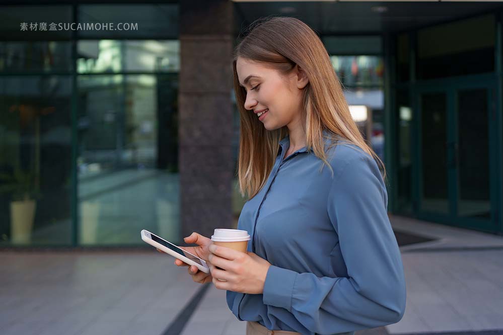 美丽的年轻女子在她的智能手机设备中使用一个应用程序在商务大楼附近发送短信照片beautif