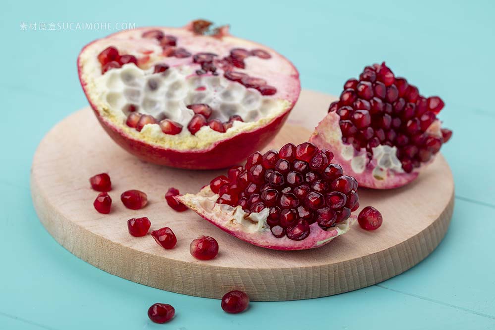 正视图石榴片浆果与石榴半切板蓝色表面front-view-pomegranate-pieces-berries-with-pomegranate-half-cutting