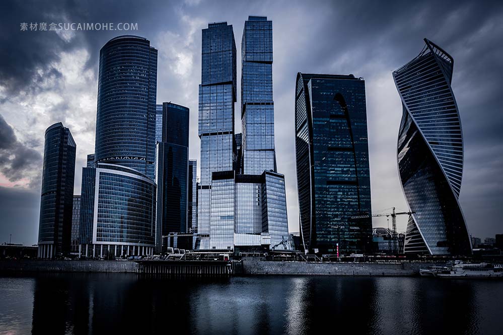 在黑暗的多云的天空下河前的灰色摩天大楼的低角度拍摄免片low-angle-shot-grey-skyscrapers-front-ri
