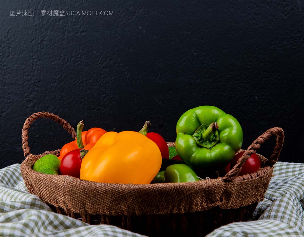 新鲜蔬菜彩色甜椒西红柿黄瓜柳条篮子格子布黑色背景