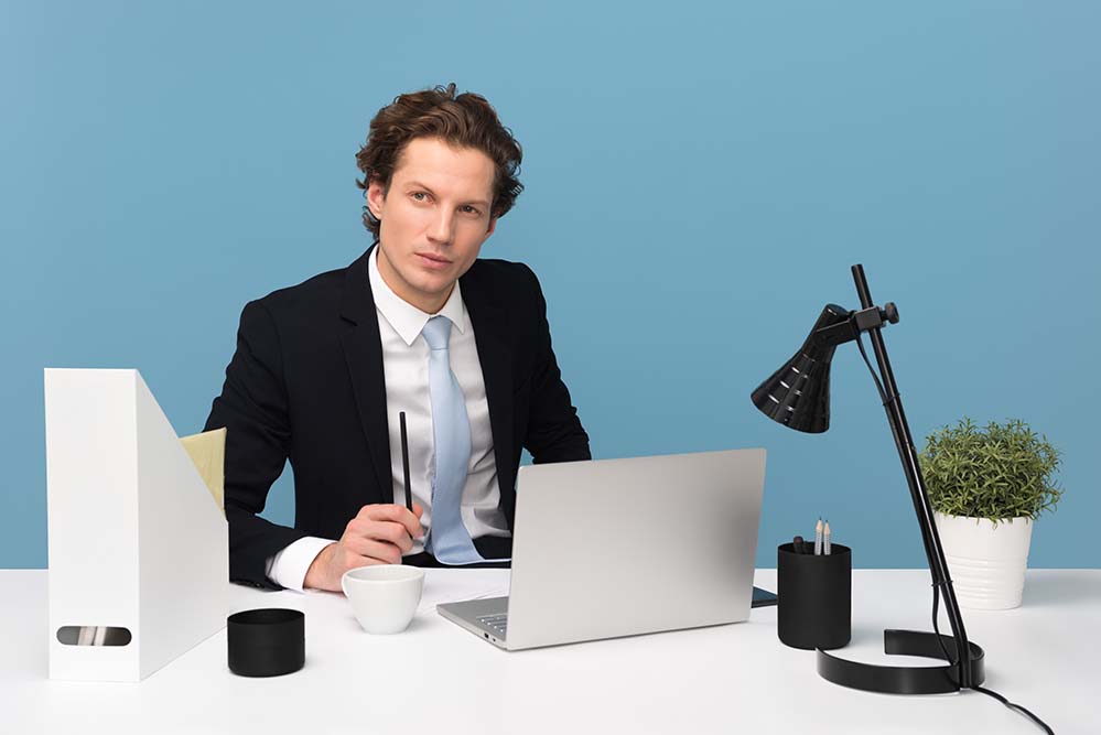 man-sitting-with-laptop-computer-on-desk-and-lamp 男人 工作 商务 电脑 笔记本 台灯书架